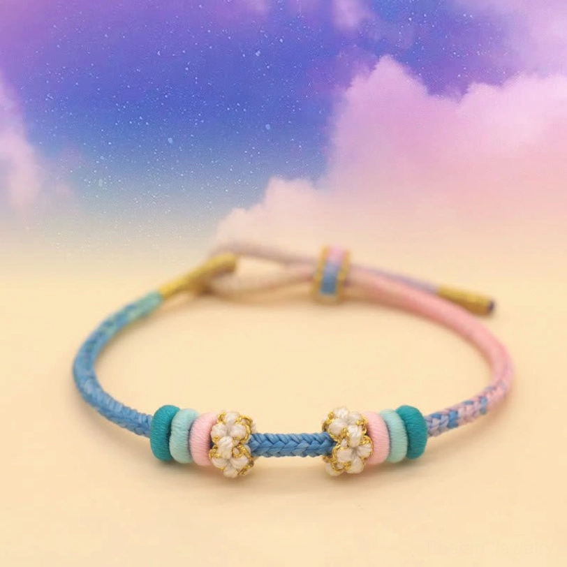 Blue and pink pastel braided peace knot bracelet with floral beads on starry sky gradient backdrop
