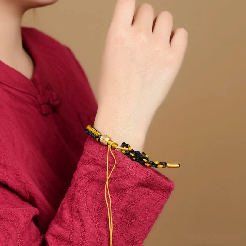 Tibetan om mani padme hum bracelet worn on left wrist with adjustable tail cord on red traditional clothing