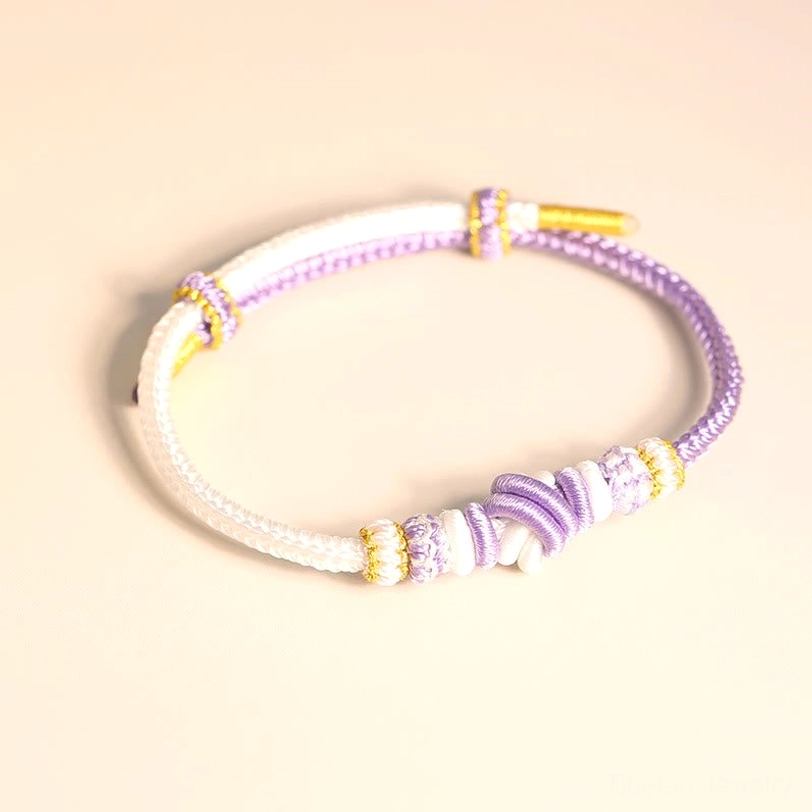 White and purple Tibetan blessing bracelet showing intricate eight-thread knot braiding and spiritual symbolism detail