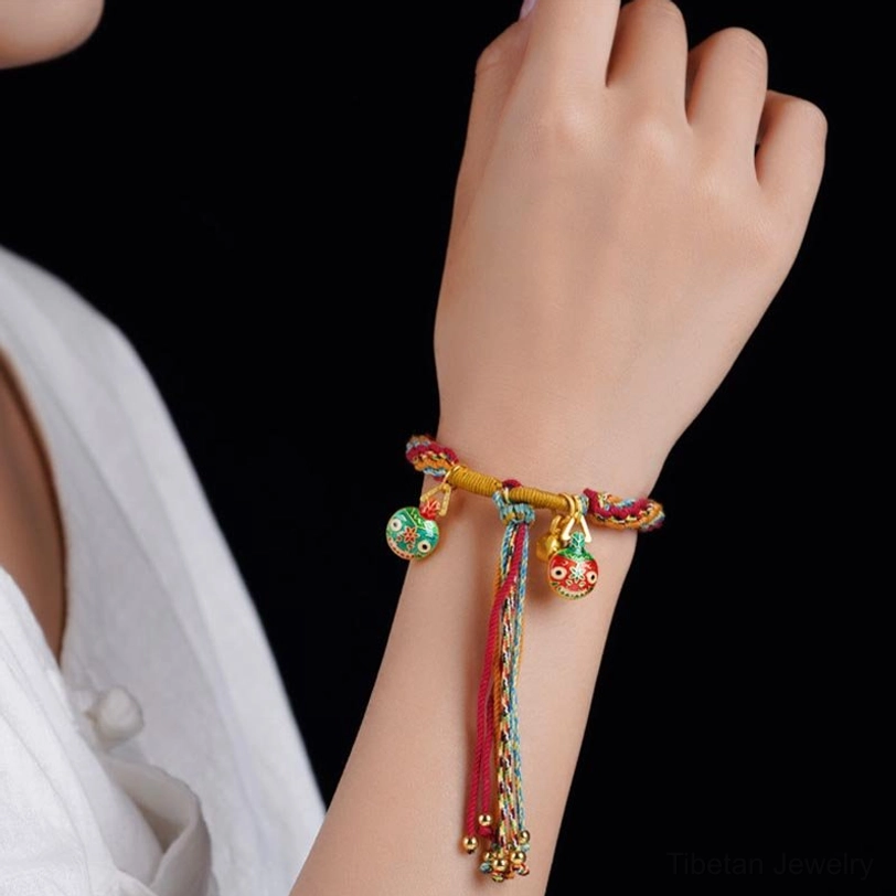 Tibetan gold beast family blessing bracelet worn on wrist with enamel pendant and tassel