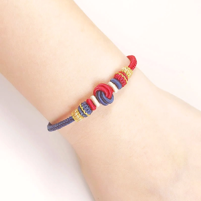 Tibetan peace knot protection bracelet worn on wrist showing detailed braided cord and spiritual knot design