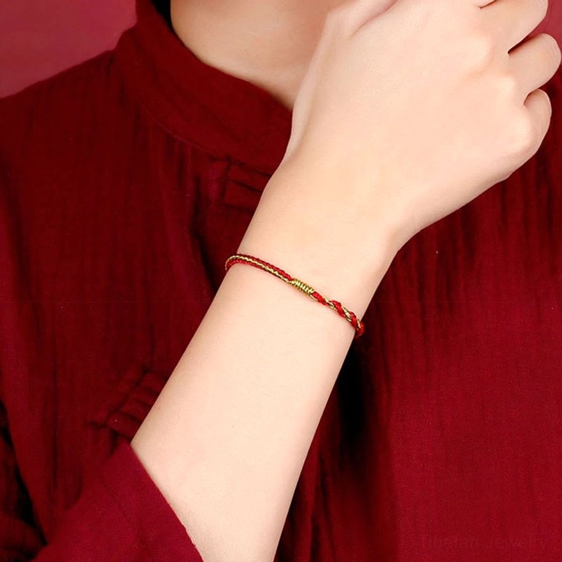 Wrist wearing thin red and gold Tibetan protection bracelet with traditional clothing close-up