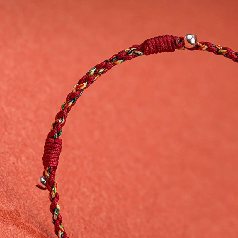 Close-up detail of Tibetan multicolor braided bracelet clasp showing woven knot fastener and copper bead adjustment mechanism