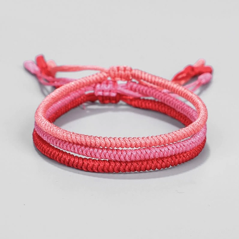 Single Tibetan braided bracelet in light pink with adjustable woven tassels - flat lay front view