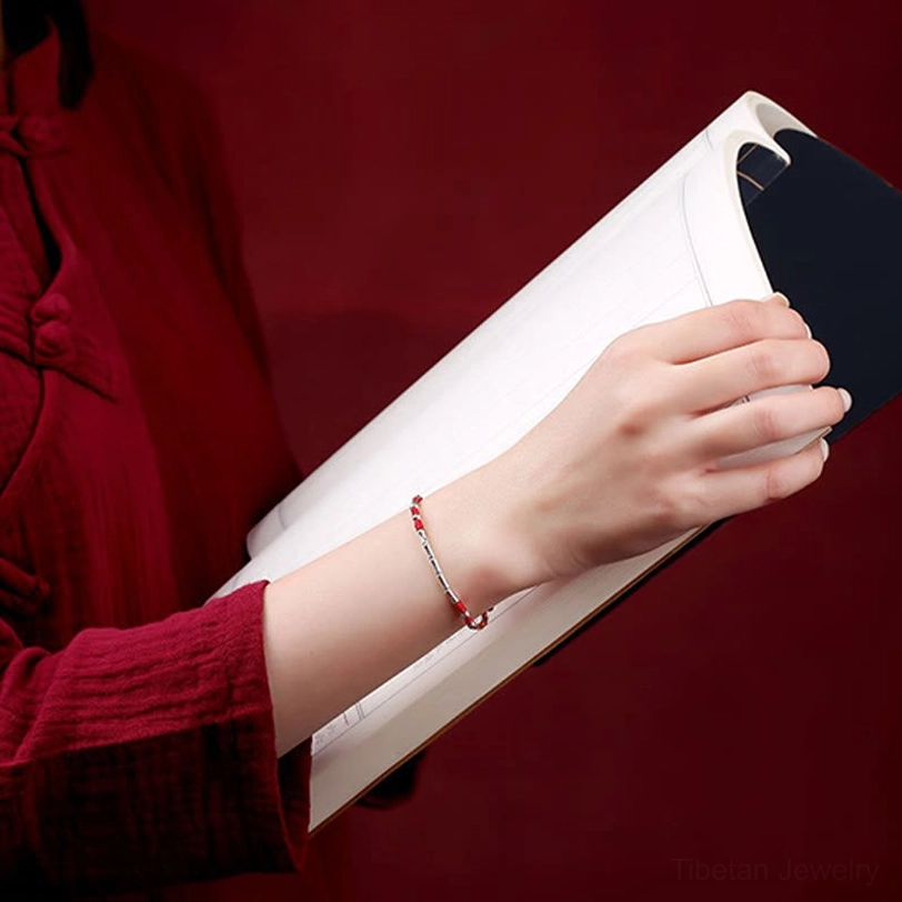 Slim Tibetan handmade braided protection bracelet worn on wrist with silver accents, close-up wearing demonstration