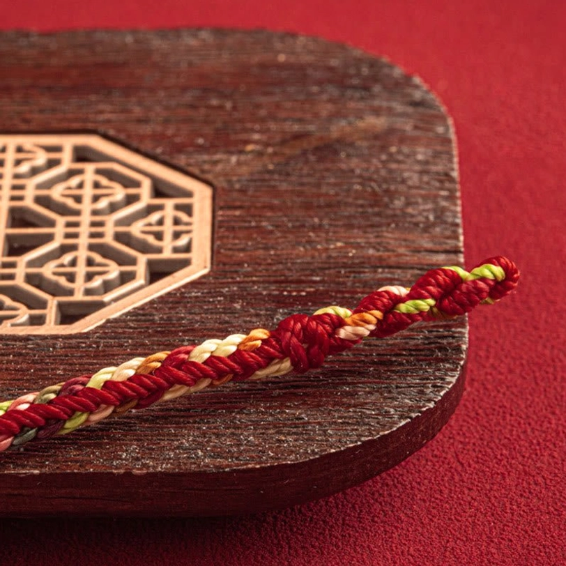 Close-up detail of twisted multicolor braided cord segment from Tibetan protection bracelet, texture and weaving pattern
