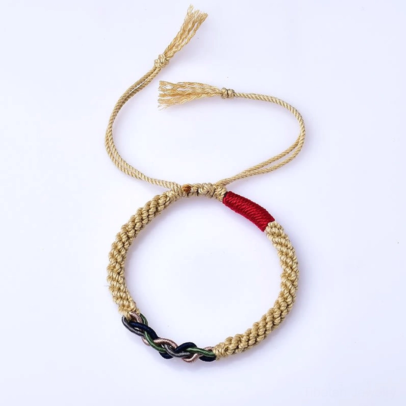 Overhead close-up of adjustable Tibetan cotton rope luck bracelet featuring knitted golden rope, red fabric accent, and mixed-color twisted knot on white background