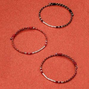 Three assorted handmade Tibetan braided protection bracelets in different color combinations with silver beads, flat lay display