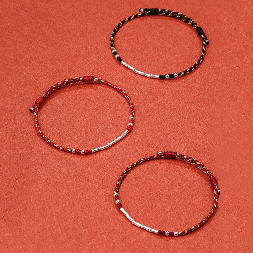 Three assorted handmade Tibetan braided protection bracelets in different color combinations with silver beads, flat lay display