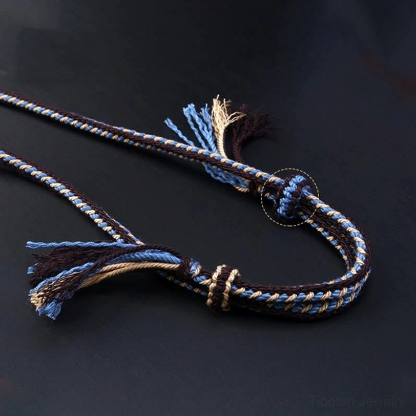 Tibetan braided necklace cord detail with blue-brown woven pattern and frayed tassel ends