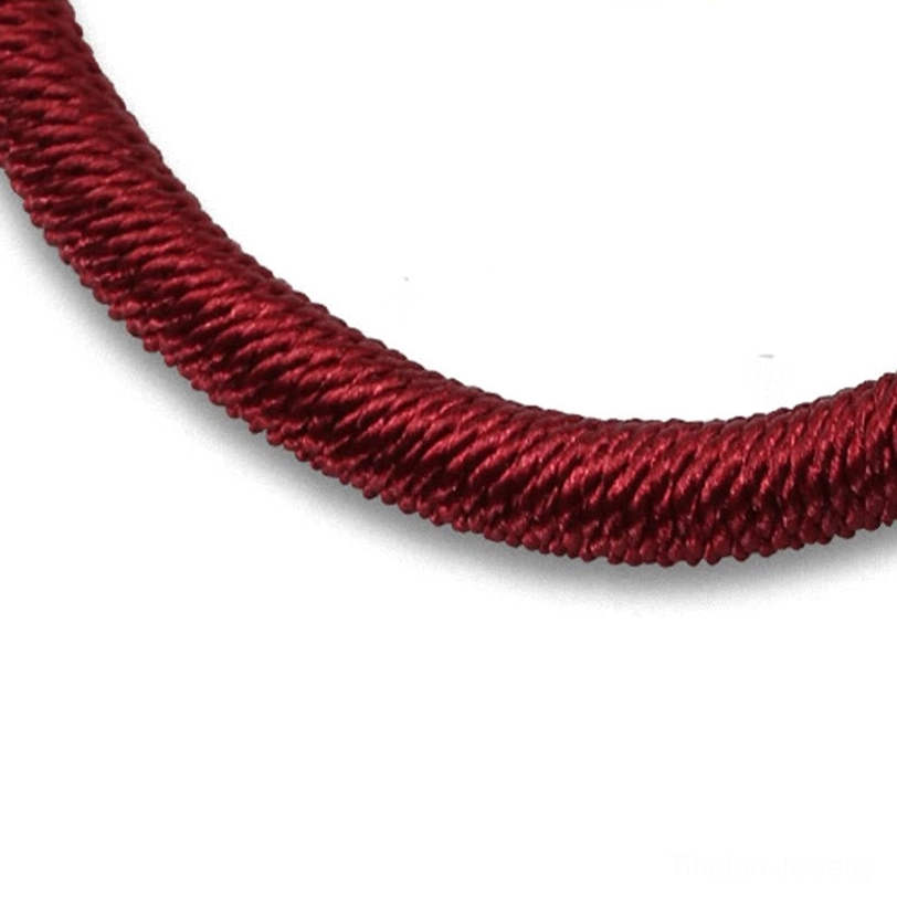 Close-up macro view of wine red braided rope showing tight twisted braided texture and weaving detail on white background