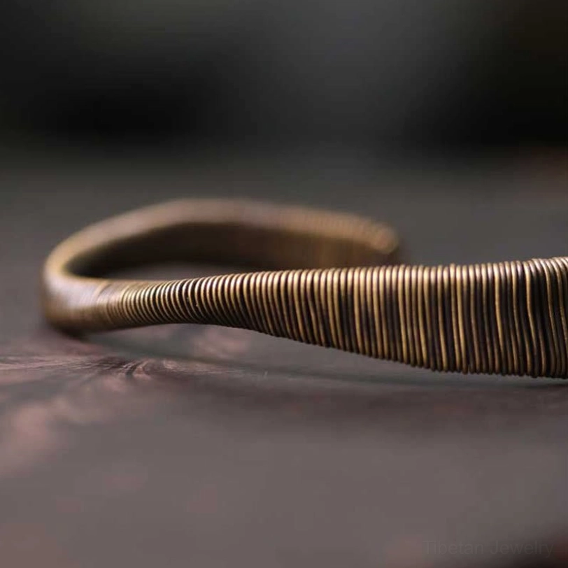 Close-up detail of hand-wrapped brass wire craftsmanship on Tibetan cuff bracelet showing texture and artisanal quality