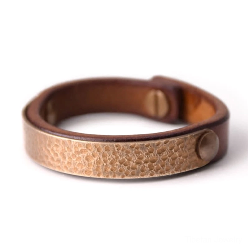 Tibetan prosperity bracelet featuring light gold hammered brass panel with round rivet closure on vintage brown leather, overhead front view