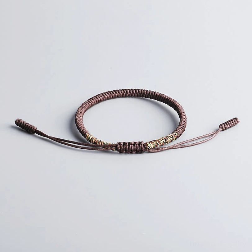Thin brown Tibetan braided protective cord bracelet with decorative knot and adjustable ties