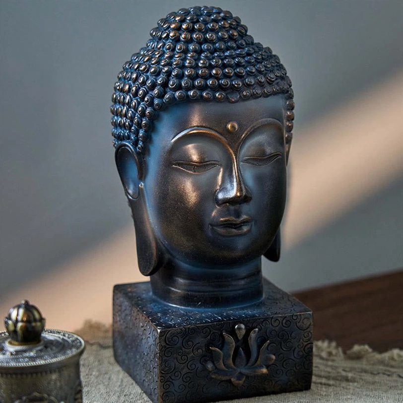 Tibetan Buddha sculpture showing detailed facial features and curly hair styling, three-quarter view on linen with incense accessories