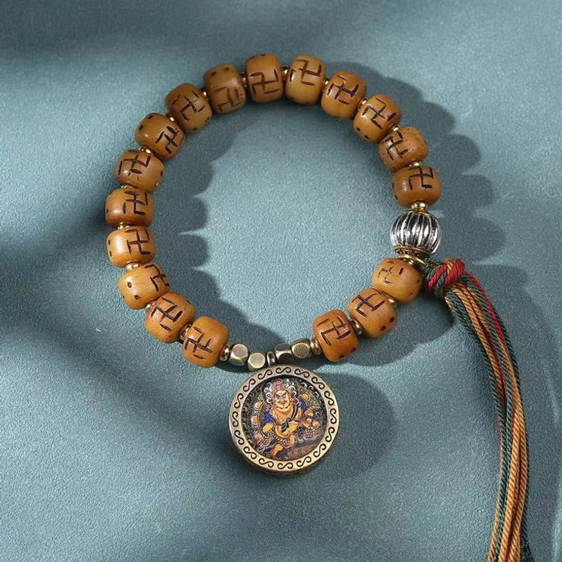 Tibetan Buddha pendant bracelet with carved camel bone barrel beads, bronze Buddha plaque, silver accents, and brown-red tassel - overhead view