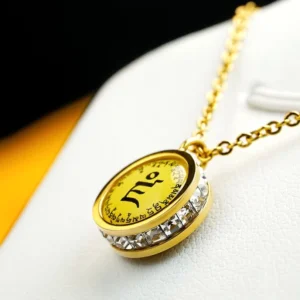 Close-up oblique view of Tibetan mantra pendant showing intricate gold frame and yellow mantra panel with crystal studded rim