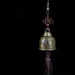 Tibetan Buddha face wind chime bell with bronze finish and brown tassel, handcrafted zinc alloy spiritual decoration