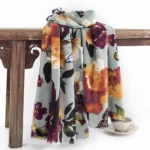 Tibetan butterfly floral shawl in dusty blue hanging on vintage wooden furniture display