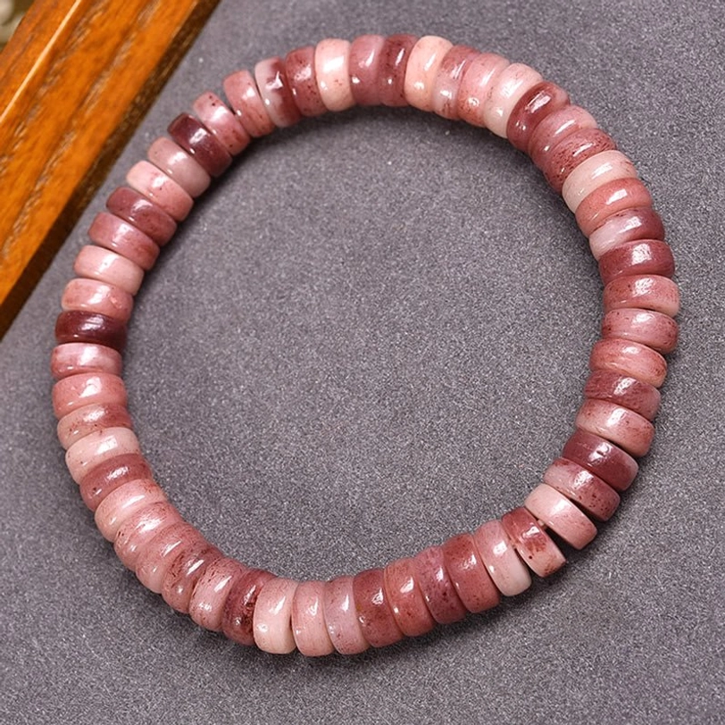 Tibetan camel bone beaded bracelet with gradient rose-pink disc beads on premium elastic string, overhead view on natural fabric