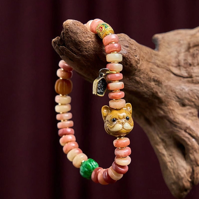 Side angle view of Tibetan pug luck bracelet with mixed pink and beige camel bone beads and metal pendant on dark red fabric