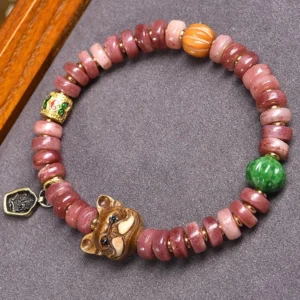Tibetan camel bone pug luck bracelet with pink beads, green jade accent, and metal pug charm on gray cloth background