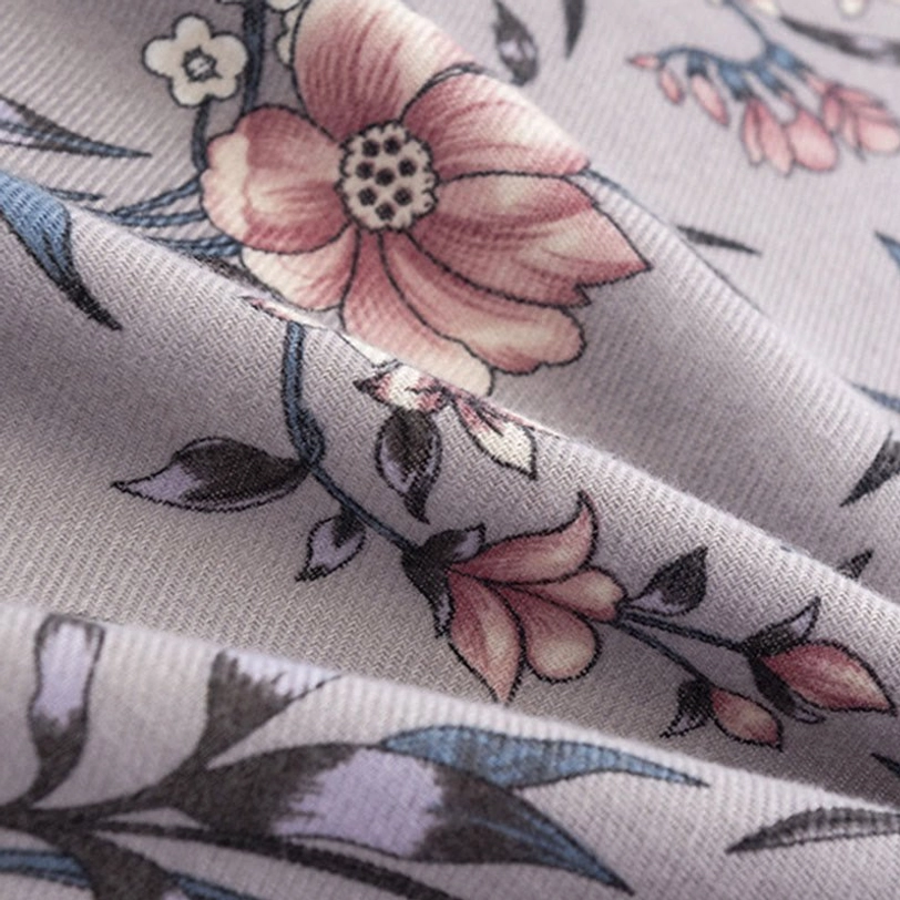 Single camellia bloom print detail on Tibetan scarf, lifelike pink flower on grey base showing fine fabric weave quality