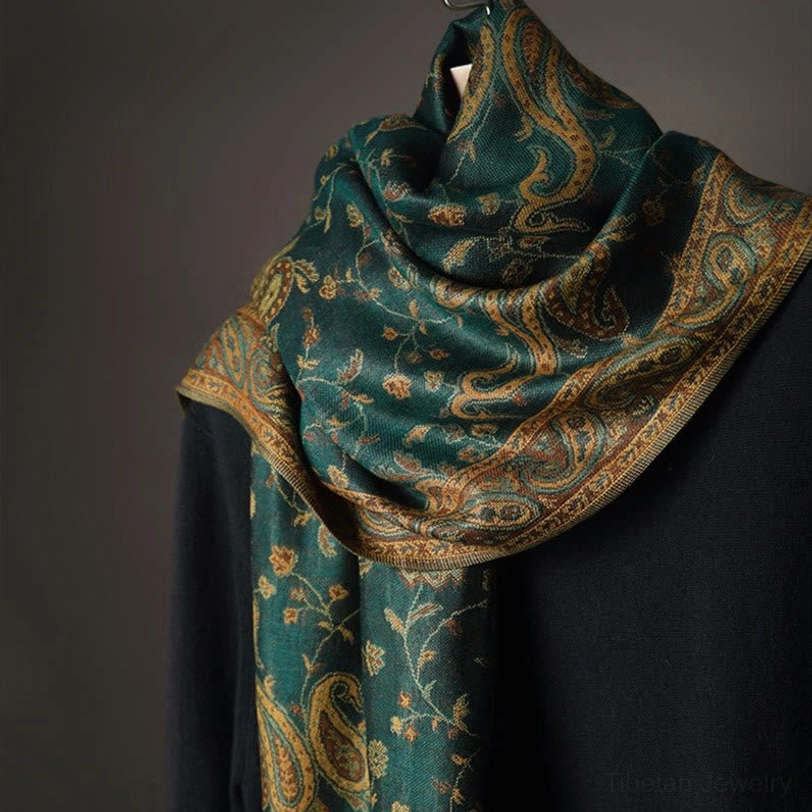 Close-up detail of soft woven tibetan paisley fabric showing teal base with intricate gold-brown floral motifs