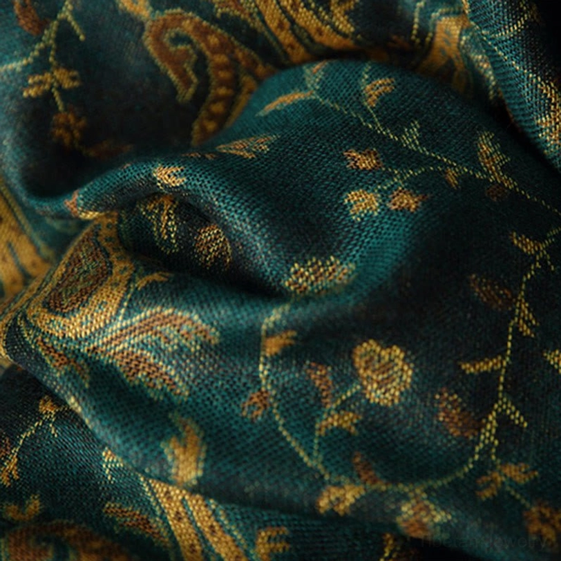 Detailed macro view of tibetan cashew flower paisley textile showing intricate woven gold and brown pattern on teal