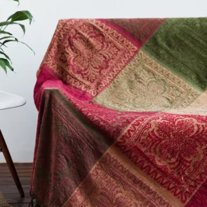 Close-up detail of intricate floral woven design on handmade Tibetan chenille blanket, featuring burgundy and emerald green jacquard weave