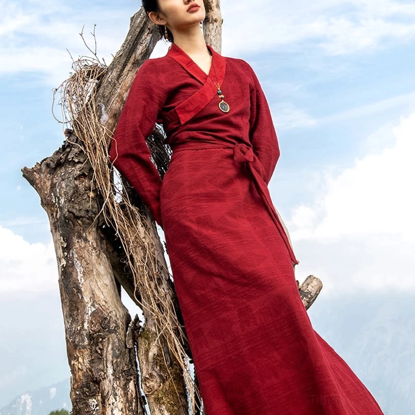 Tibetan wrap maxi dress with auspicious cloud pattern in burgundy, full-length outdoor model shot showing cross V-neck and waist tie detail