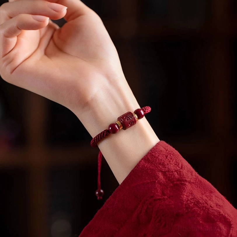 Tibetan cinnabar blessing bracelet worn on wrist showing adjustable pull cord and slim fit - close-up side view with dark background