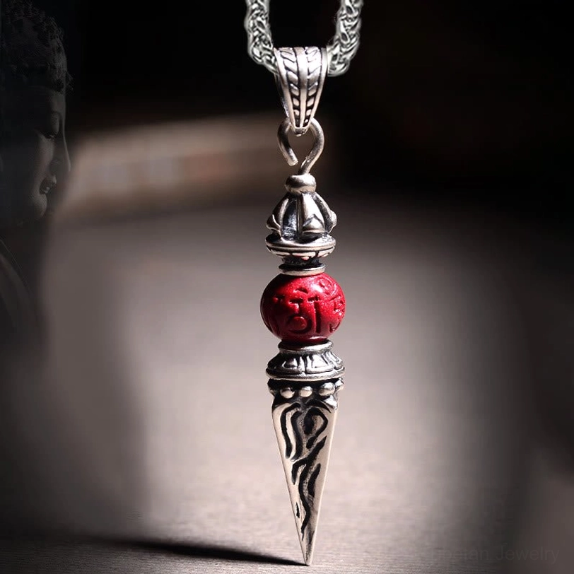 Tibetan cinnabar dorje vajra pendant necklace front close-up view with intricate Sanskrit engravings and red cinnabar bead