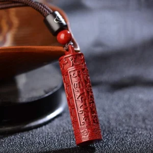 Tibetan cinnabar mantra necklace close-up showing red carved pendant with black cord and accent beads on wooden display holder