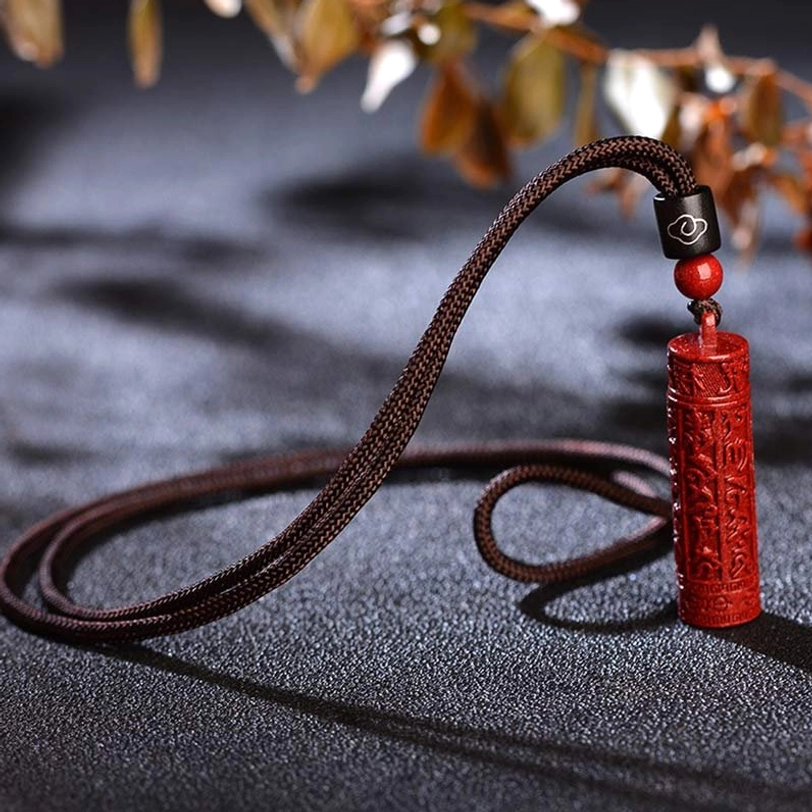 Complete Tibetan cinnabar mantra necklace set flat lay on dark fabric background showing full pendant length