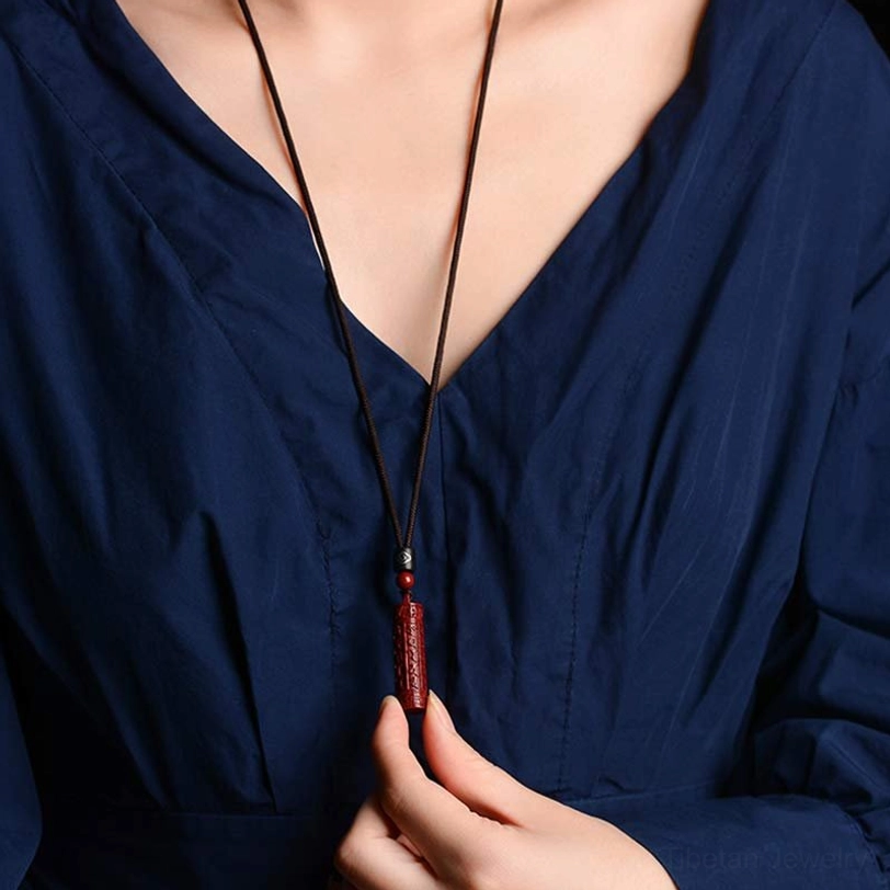 Woman wearing Tibetan cinnabar amulet necklace at collarbone, daily wear styling with black cord