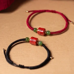 Red and black Tibetan cinnabar om mani padme hum bracelets side by side, showing braided rope styles and jade bead details