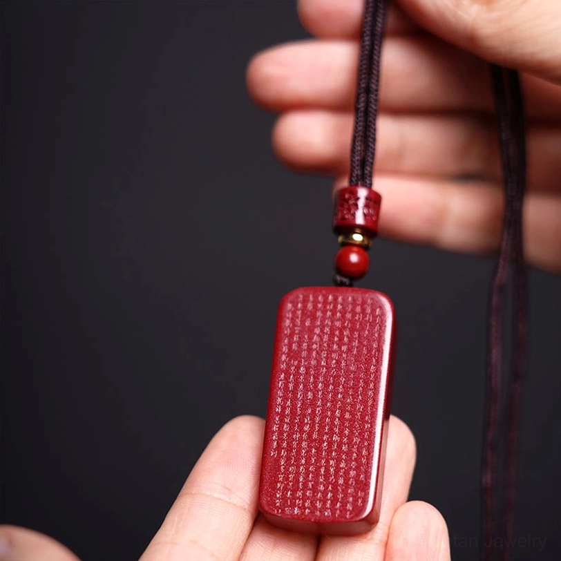 Tibetan cinnabar pendant necklace detailed close-up showing texture and hand-carved craftsmanship of Heart Sutra text