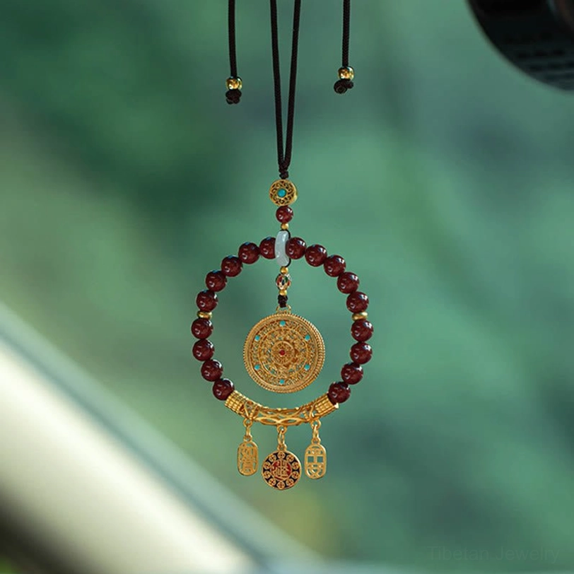Tibetan cinnabar ruyi car hanging ornament overhead view showing maroon beads and gold filigree pendant with enamel blessing charms
