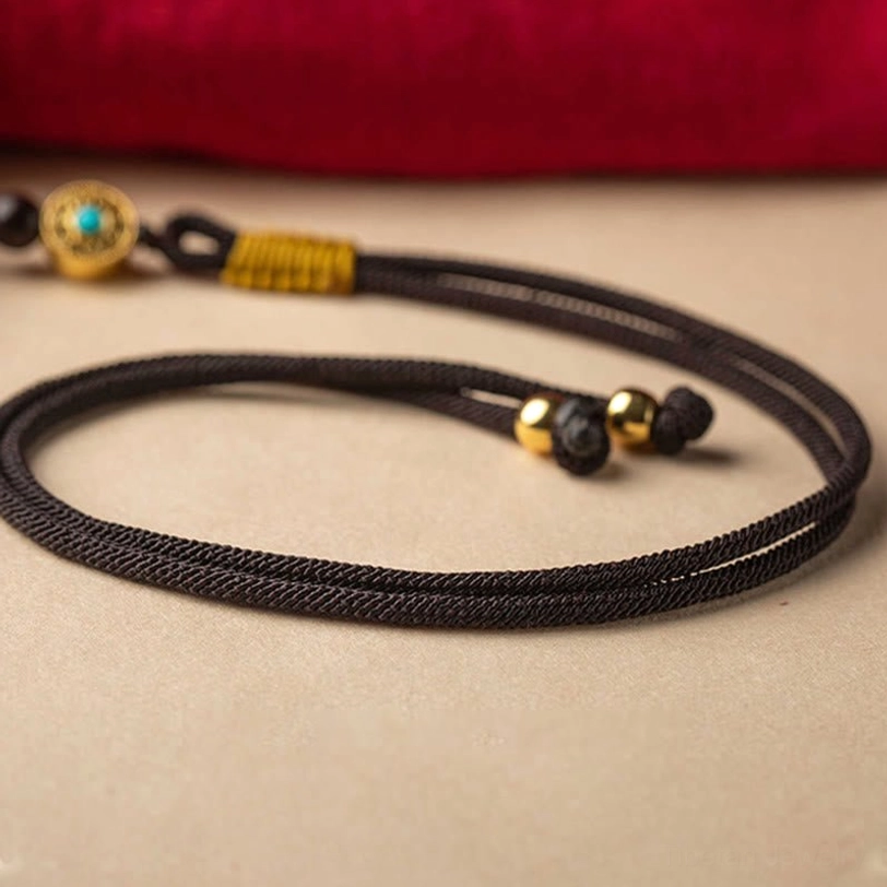 Alternative angle of tibetan cinnabar ruyi peace ornament showing maroon bead quality and gold lucky charm details