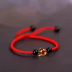 Red Tibetan citrine and black obsidian beaded bracelet with King Kong knot, displayed from an oblique angle on dark background