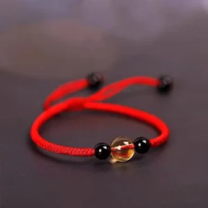Red Tibetan citrine and black obsidian beaded bracelet with King Kong knot, displayed from an oblique angle on dark background