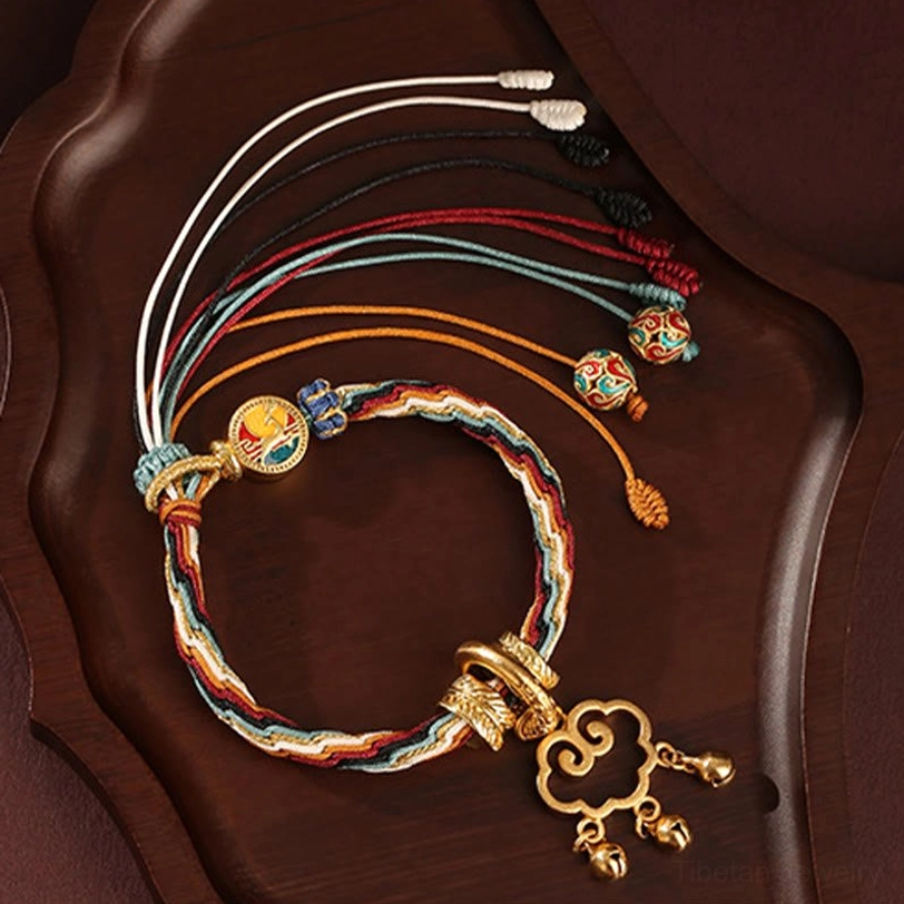 Multicolor tibetan reincarnation knot bracelet with cloud lock tassel and enamel pendants on dark serving tray