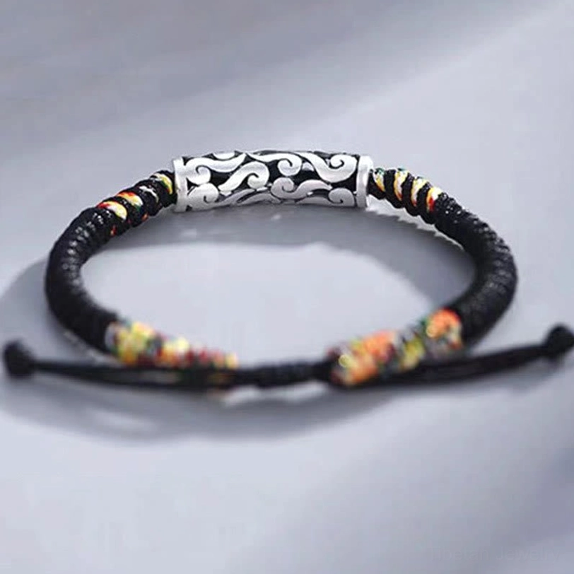 Full circular display of tibetan auspicious cloud bracelet with black braided cord and colorful woven sections on gray backdrop