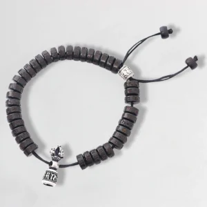 Tibetan coconut shell Om Mani Padme Hum prayer bracelet, top view featuring dark brown carved beads with silver vajra charm and adjustable black drawstring