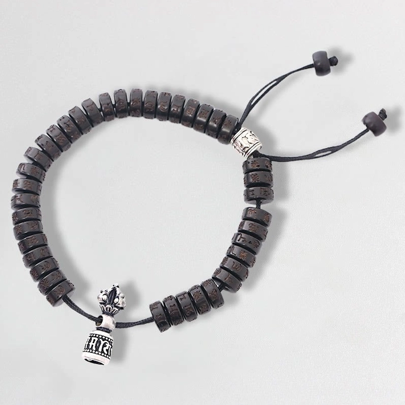 Tibetan coconut shell Om Mani Padme Hum prayer bracelet, top view featuring dark brown carved beads with silver vajra charm and adjustable black drawstring