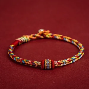 Handmade Tibetan colorful protection bracelet with braided multicolor threads, decorative knot and metal clasp on dark red background
