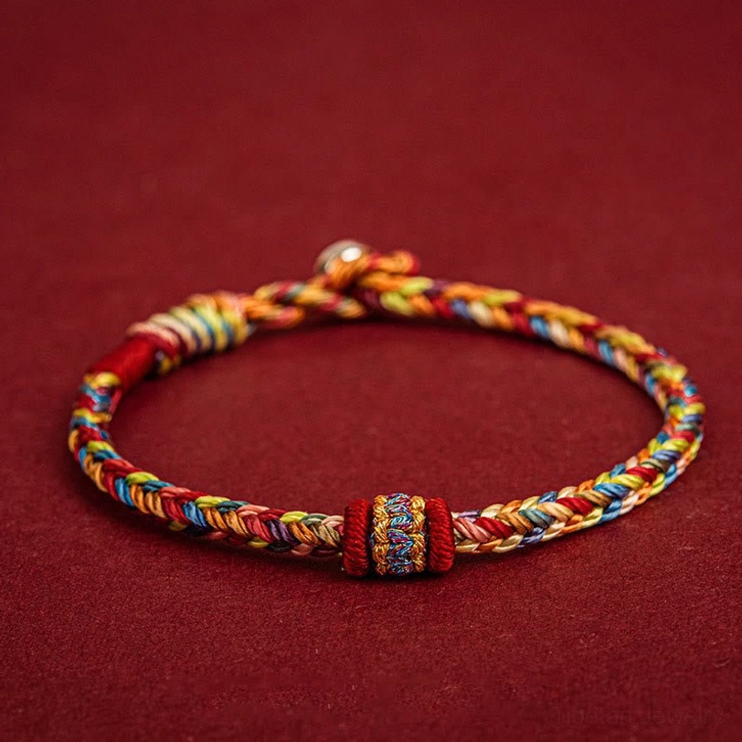 Handmade Tibetan colorful protection bracelet with braided multicolor threads, decorative knot and metal clasp on dark red background
