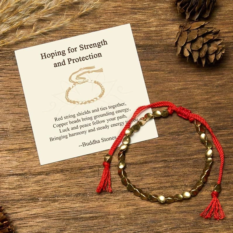 Tibetan copper beads protection bracelet with red braided cord, matte oval beads, and blessing message card on wooden surface with natural elements