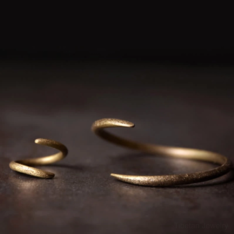 Two sizes of copper open claw cuff bracelets, bronze-gold matte finish, tapered claw ends, overhead flat lay composition